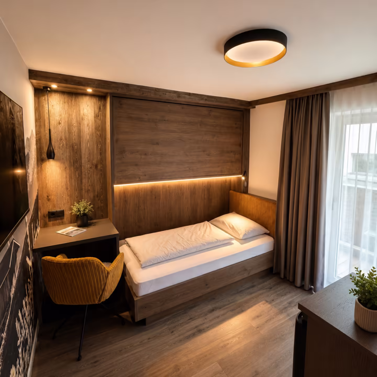 Einzelbett mit kleinem Schreibtisch und gelben Stuhl, Fenster und moderner Einrichtung